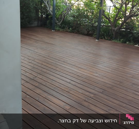 רצפת עץ עם פרגולה וגינה ברקע